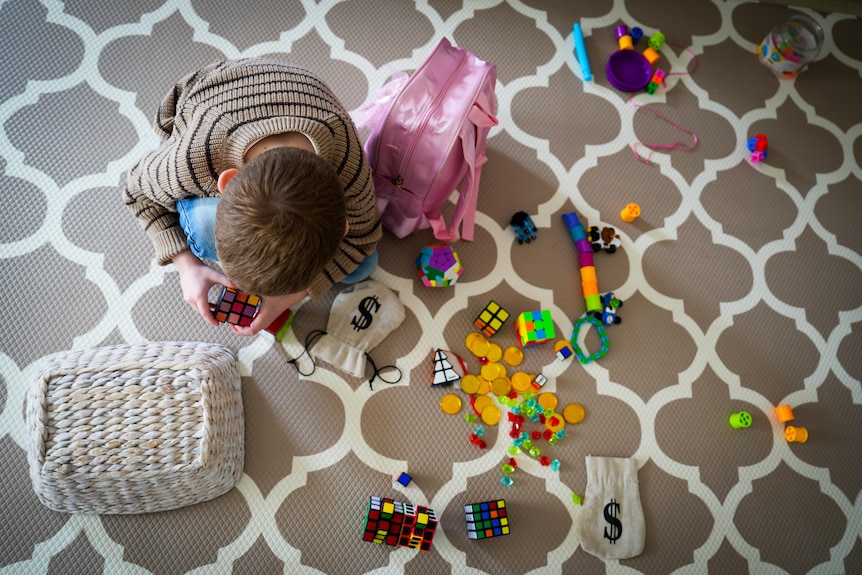 Patrick is sitting on the floor playing with blocks.