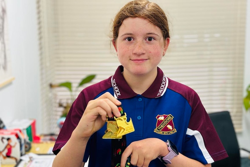 A girl with two medals around her neck smiling 