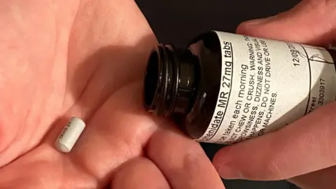 A pill in one hand with an open medicine bottle in the other