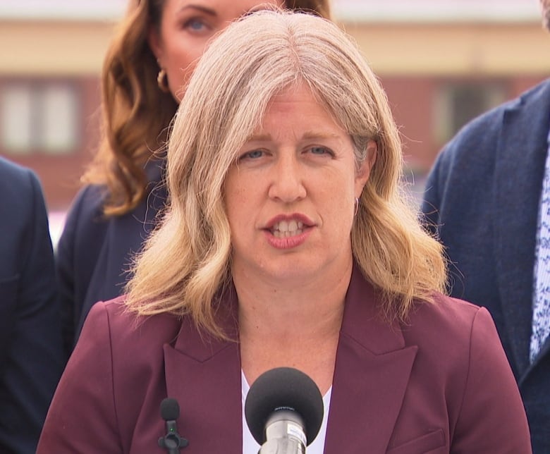 A woman with blond hair speaks into a microphone